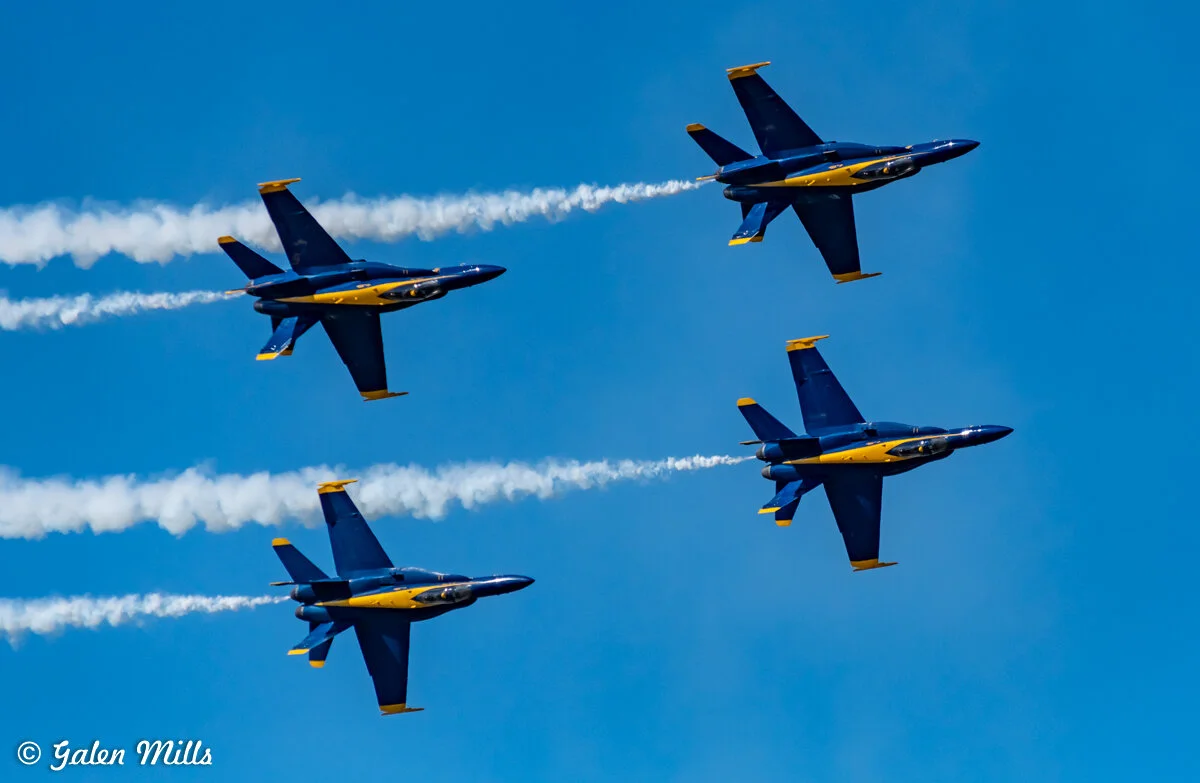 Four jet fighter planes flying in formation, leaving white vapor trails in the sky.