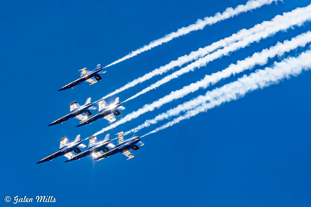 Four fighter jets flying in formation with contrails against a clear blue sky.