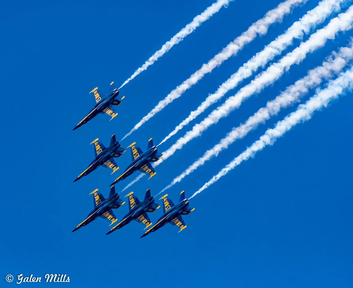 Six fighter jets in formation with vapor trails against a clear blue sky