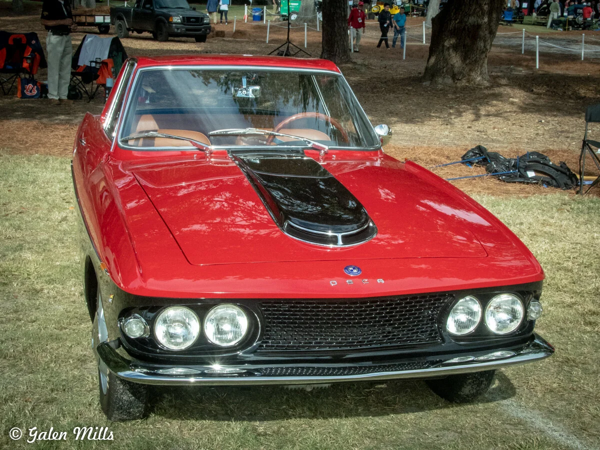Red classic sports car displayed outdoors on grass