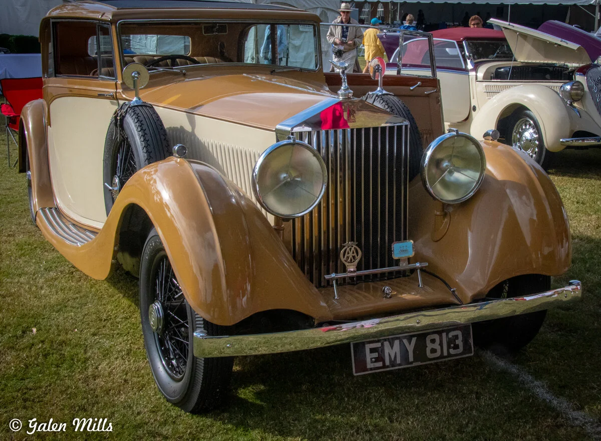 Vintage car, likely a Rolls-Royce, displayed at a car show, with distinctive two-tone paint and classic design elements.