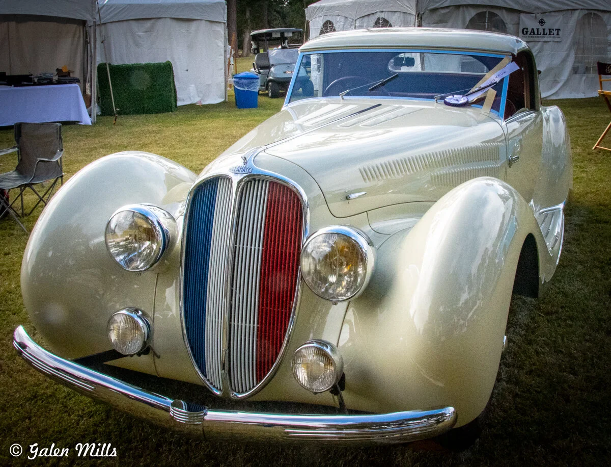Vintage Delahaye car with unique front design on display at an outdoor event, featuring distinctive headlights and a tri-color grille.