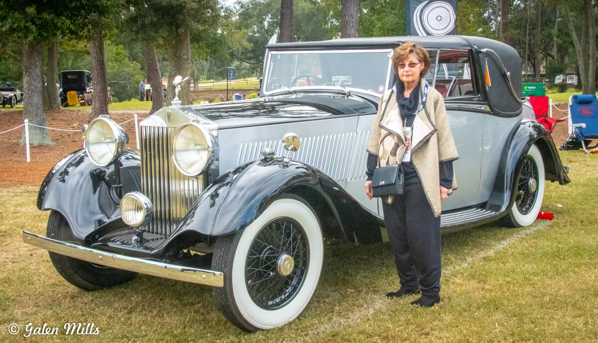 Vintage Rolls-Royce car with a person standing next to it at an outdoor event.