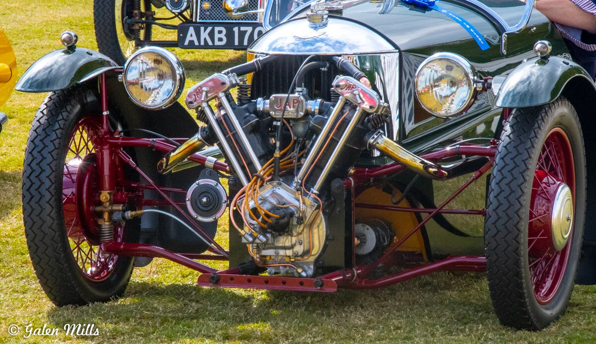 Vintage three-wheeler car with exposed engine and headlights