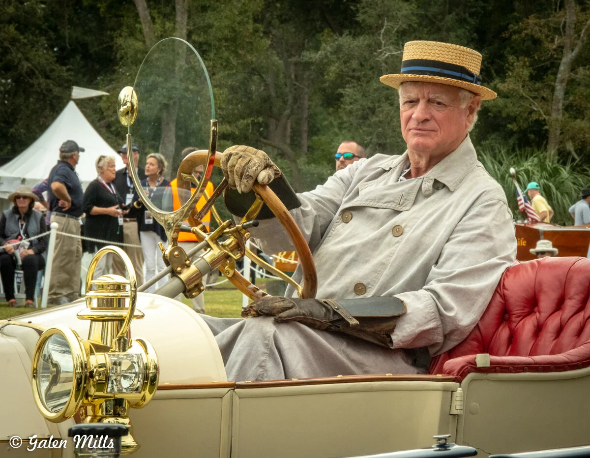 Man in vintage outfit driving classic car at car show