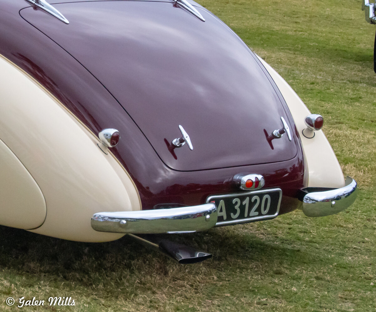 Rear view of a vintage car with two-tone paint, chrome bumpers, and license plate.