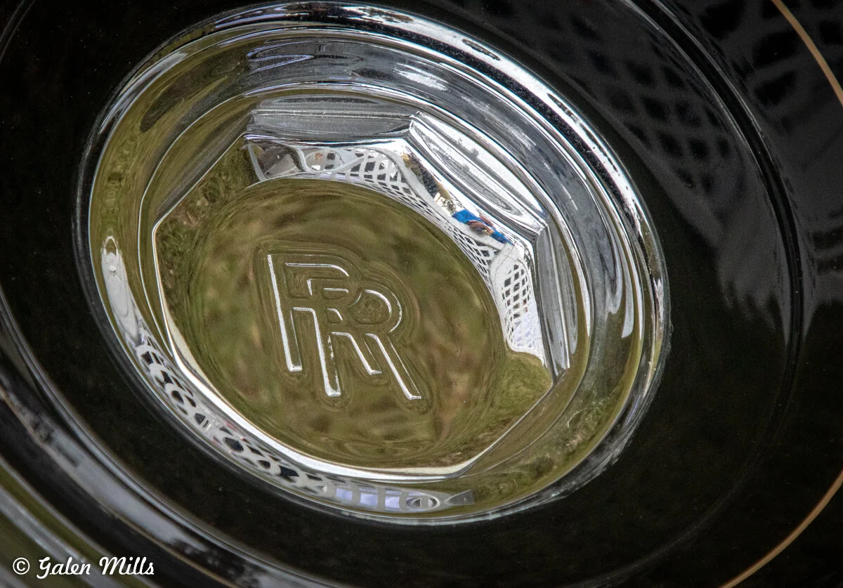 Close-up of a Rolls-Royce logo on a car hubcap.