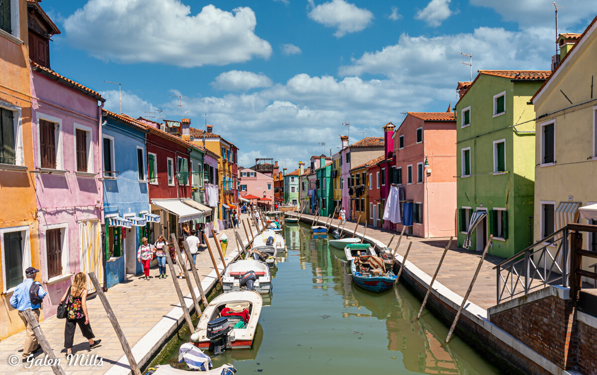 Colorful houses lining a canal with boats in Burano, Italy.