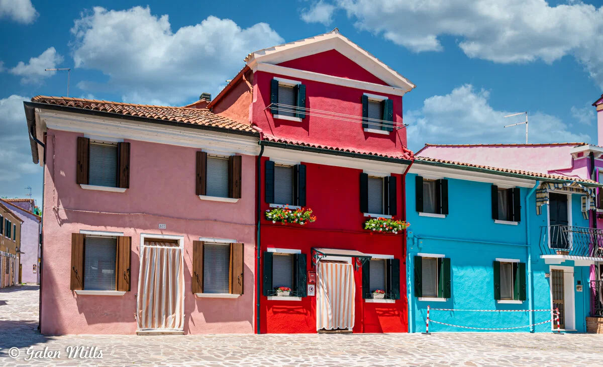 Colorful houses on Burano Island, Italy with blue sky and clouds.