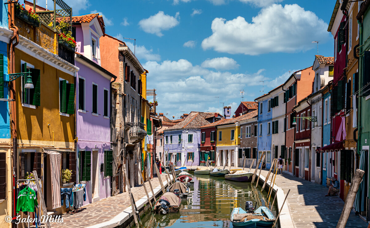 Colorful buildings and boats along a canal in Burano, Italy.