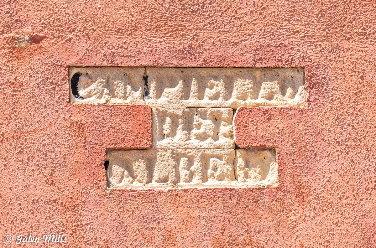A close-up of a stone wall with an embossed, partially legible inscription.