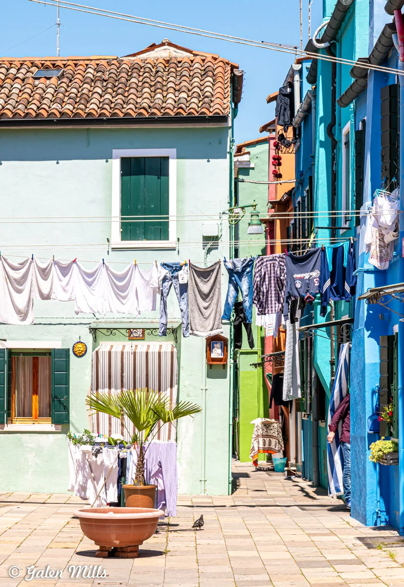 Colorful houses with clothes drying on lines in a narrow street.