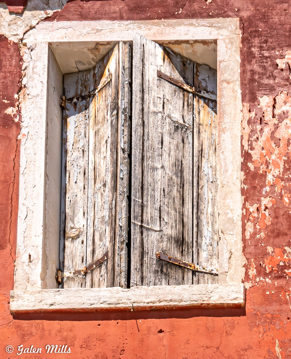 Old wooden shutters on a weathered red wall