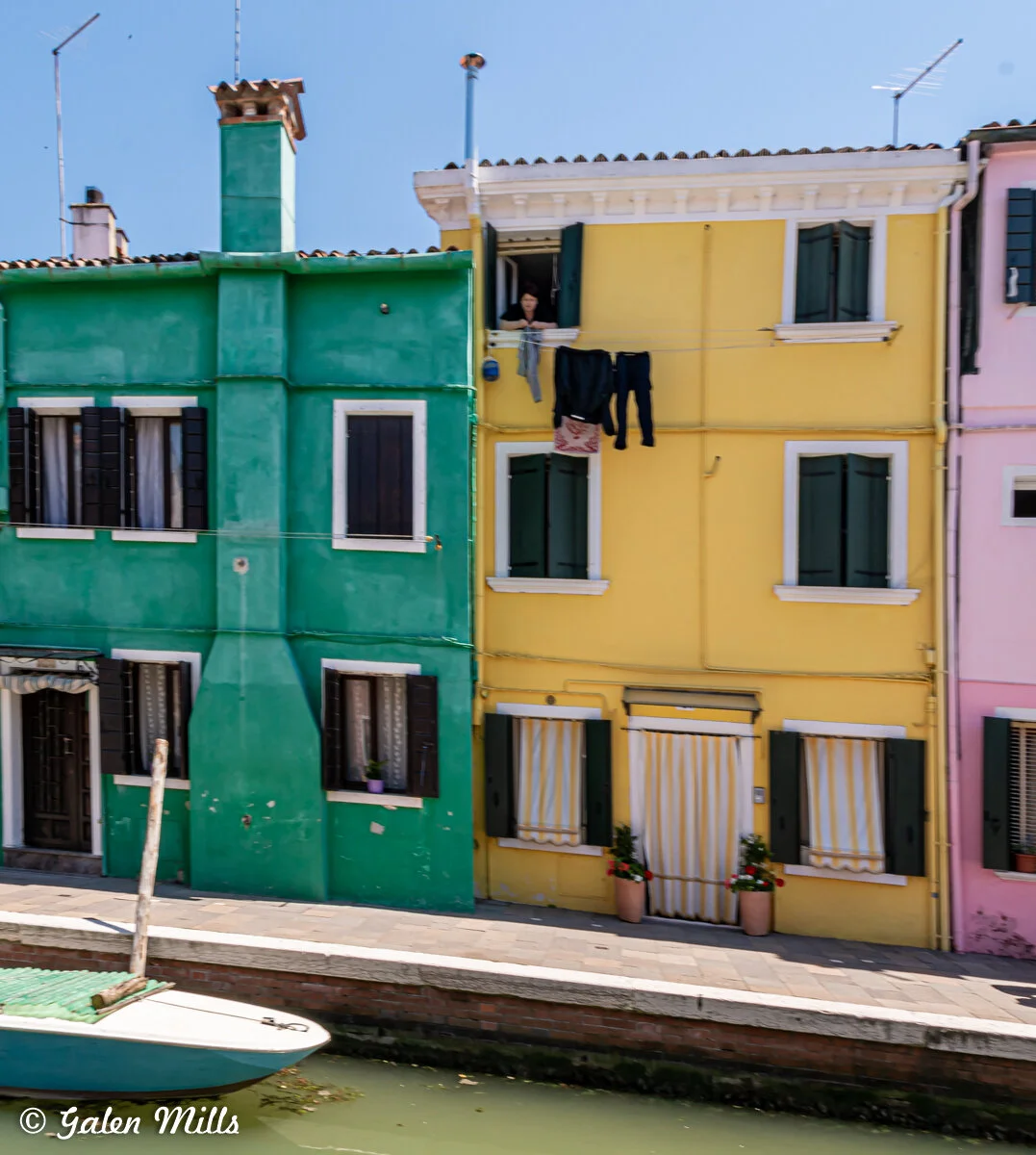 Colorful buildings beside a canal, with clothes hanging outside a yellow building.