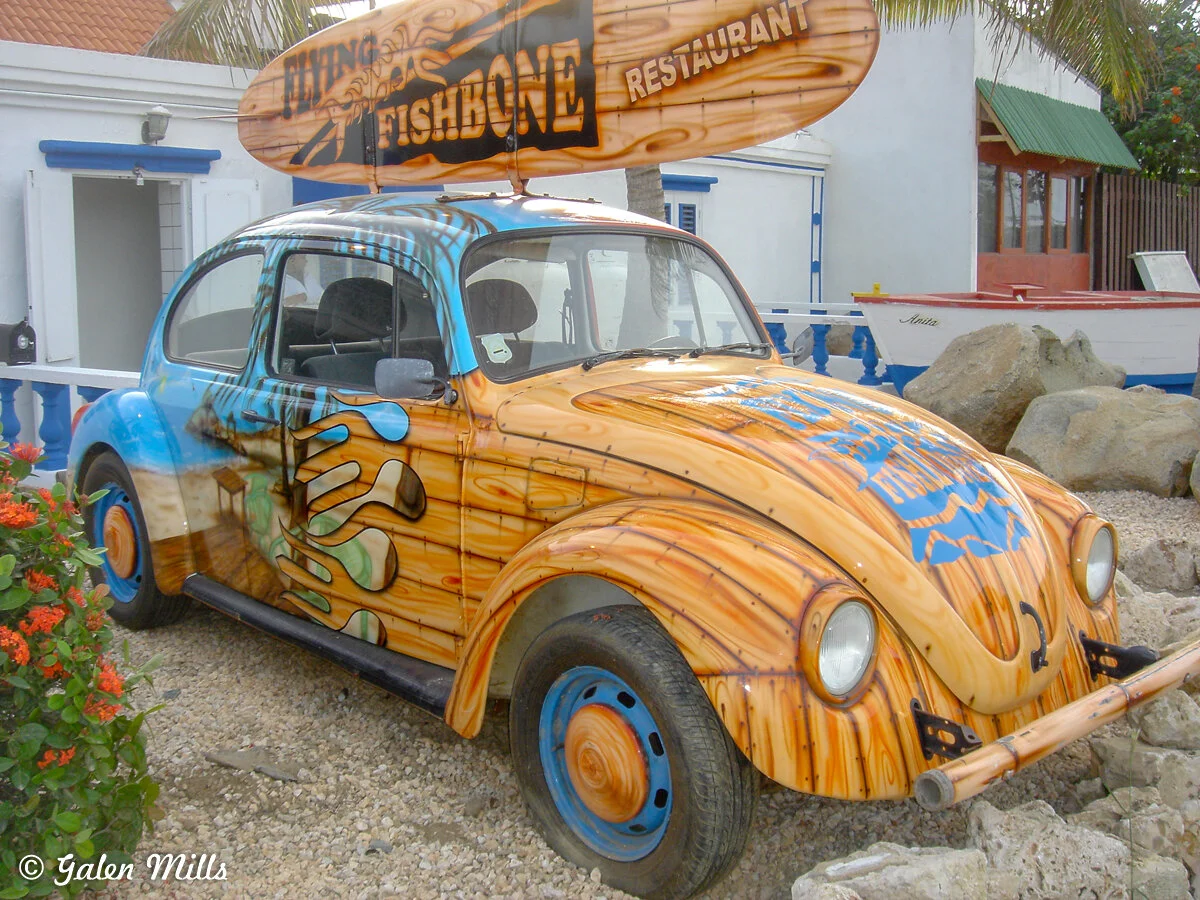 Colorfully painted Volkswagen Beetle with "Flying Fishbone Restaurant" sign