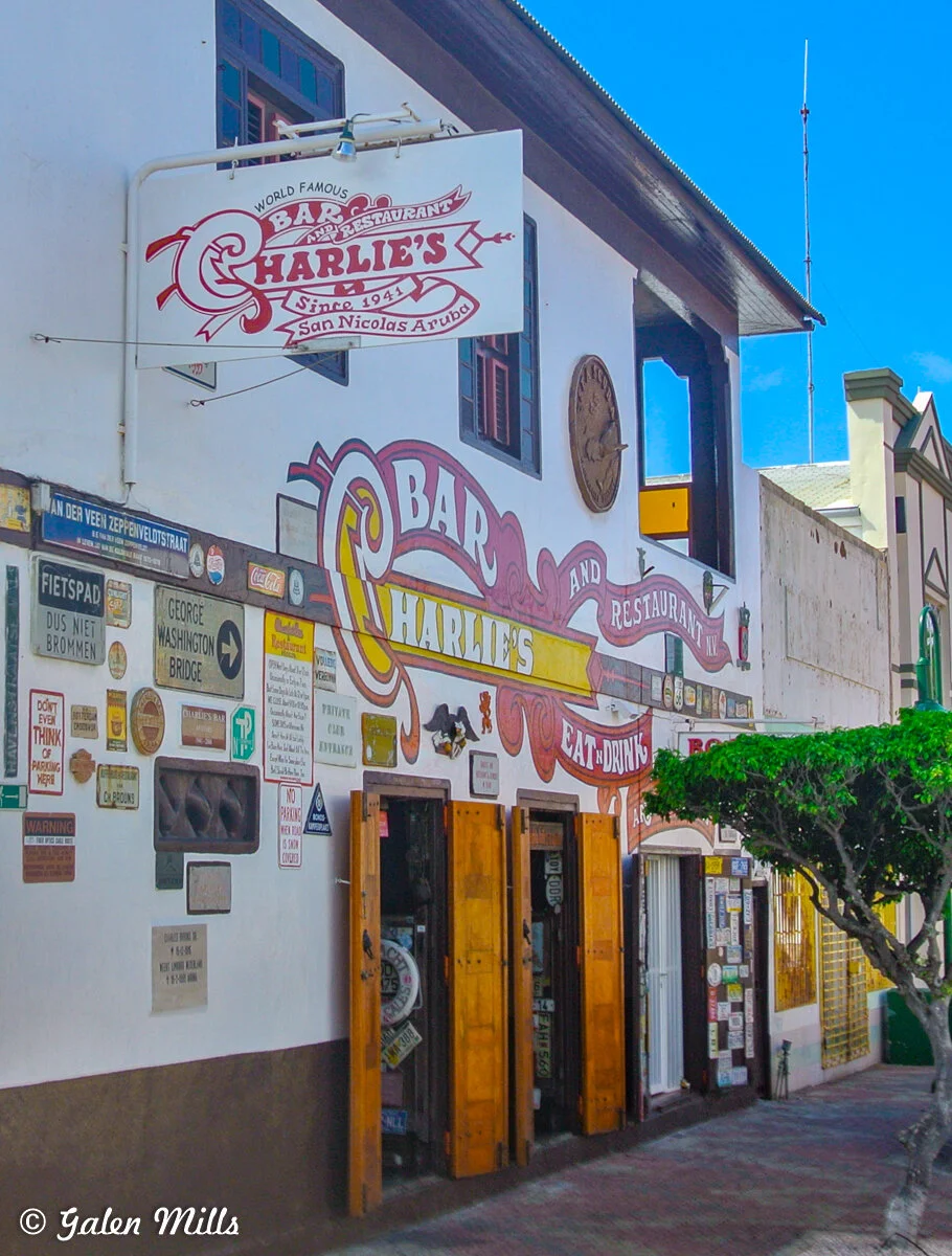 Exterior of Charlie's Bar and Restaurant in San Nicolas, Aruba, with vintage signs and a wooden facade.