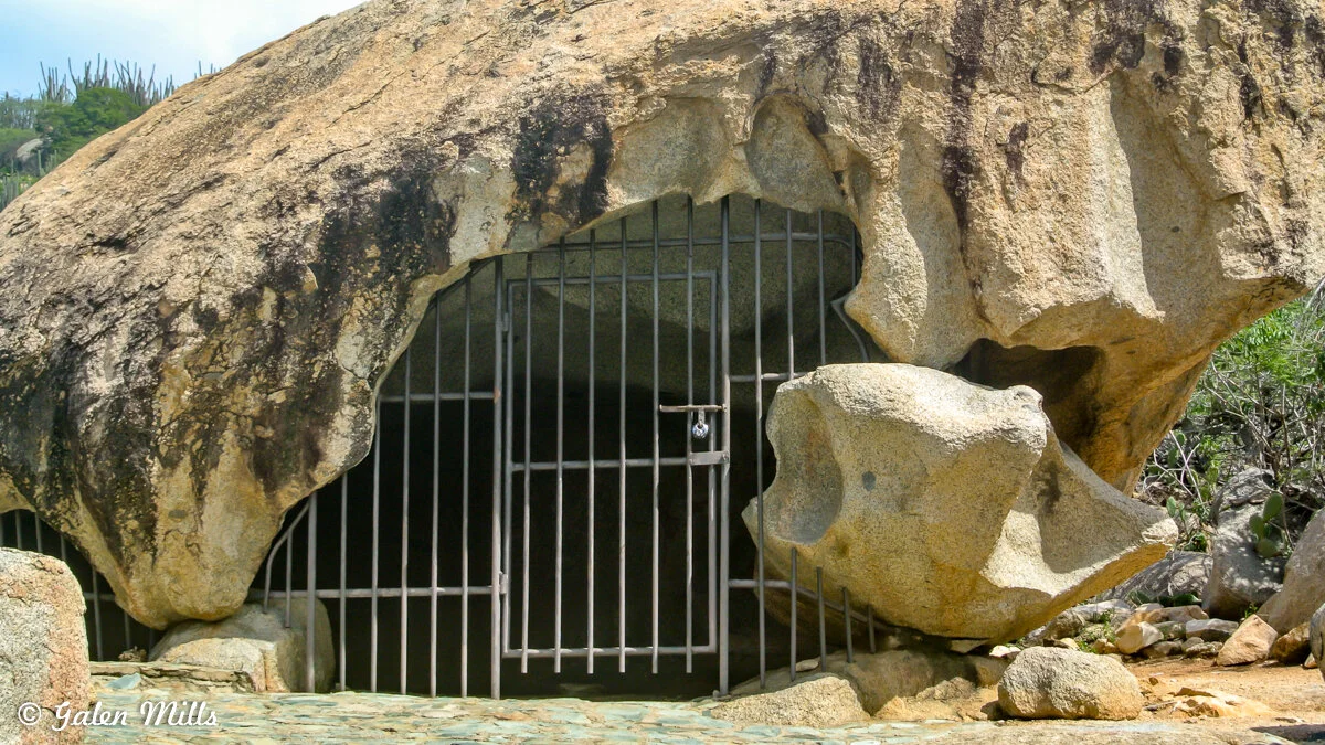 Rock formation with a barred gate entrance in a natural setting.