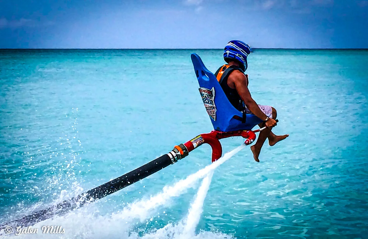 Person on a jet-powered flyboard soaring above the ocean.