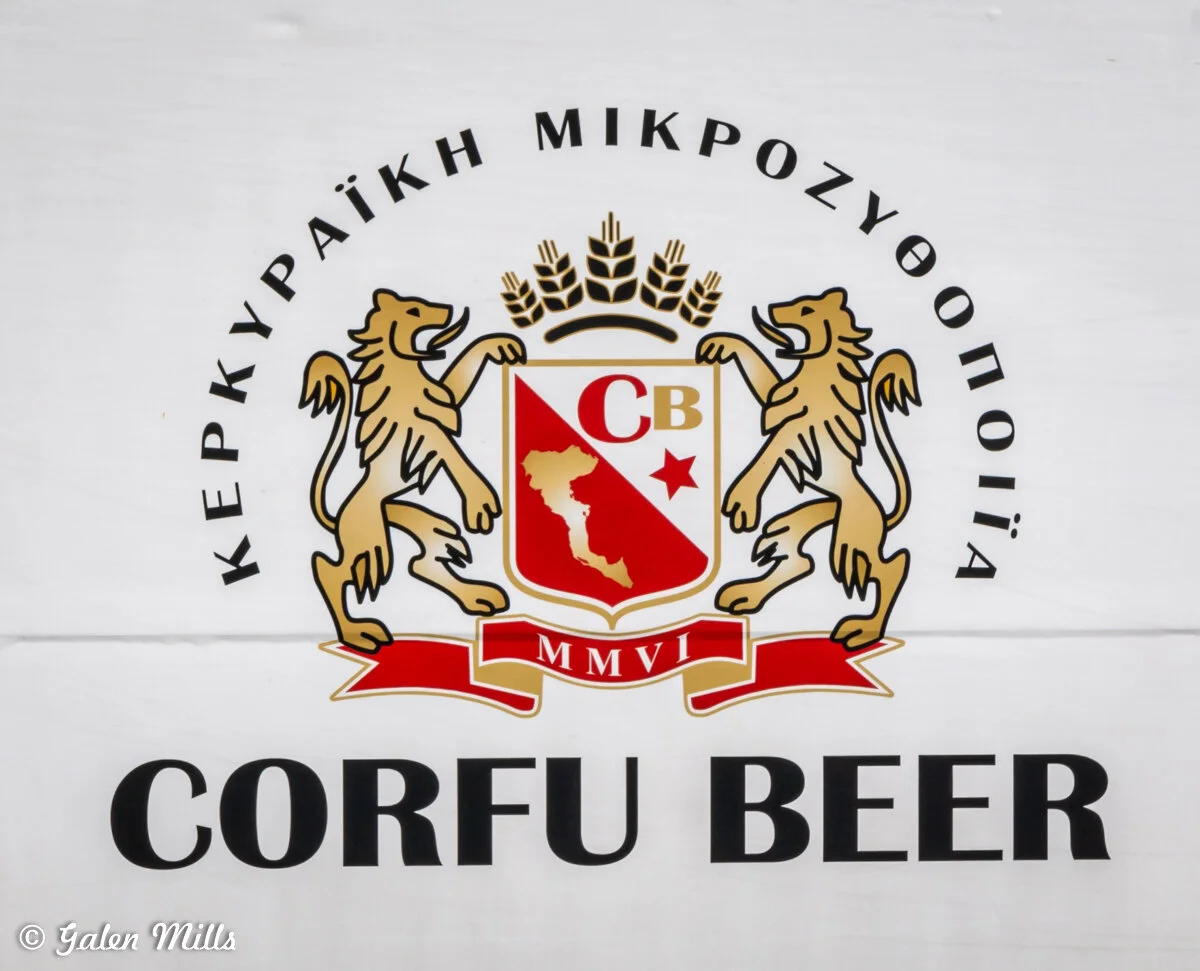 Corfu Beer logo with emblem featuring two lions, a shield with "CB" letters, and Greek text above.