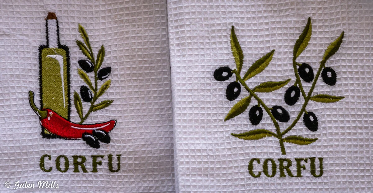 Embroidered kitchen towel with olive branch, olive oil bottle, and chili pepper, labeled 'Corfu.'