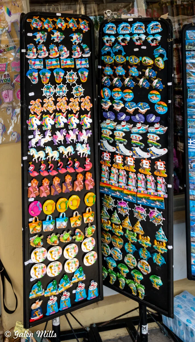 Display of colorful souvenir magnets featuring various designs including animals, unicorns, and beach-themed motifs on a stand.