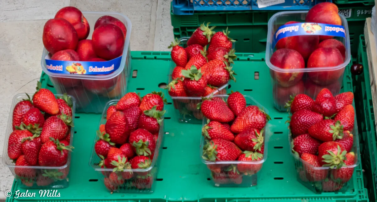 Containers of strawberries and nectarines on a green tray