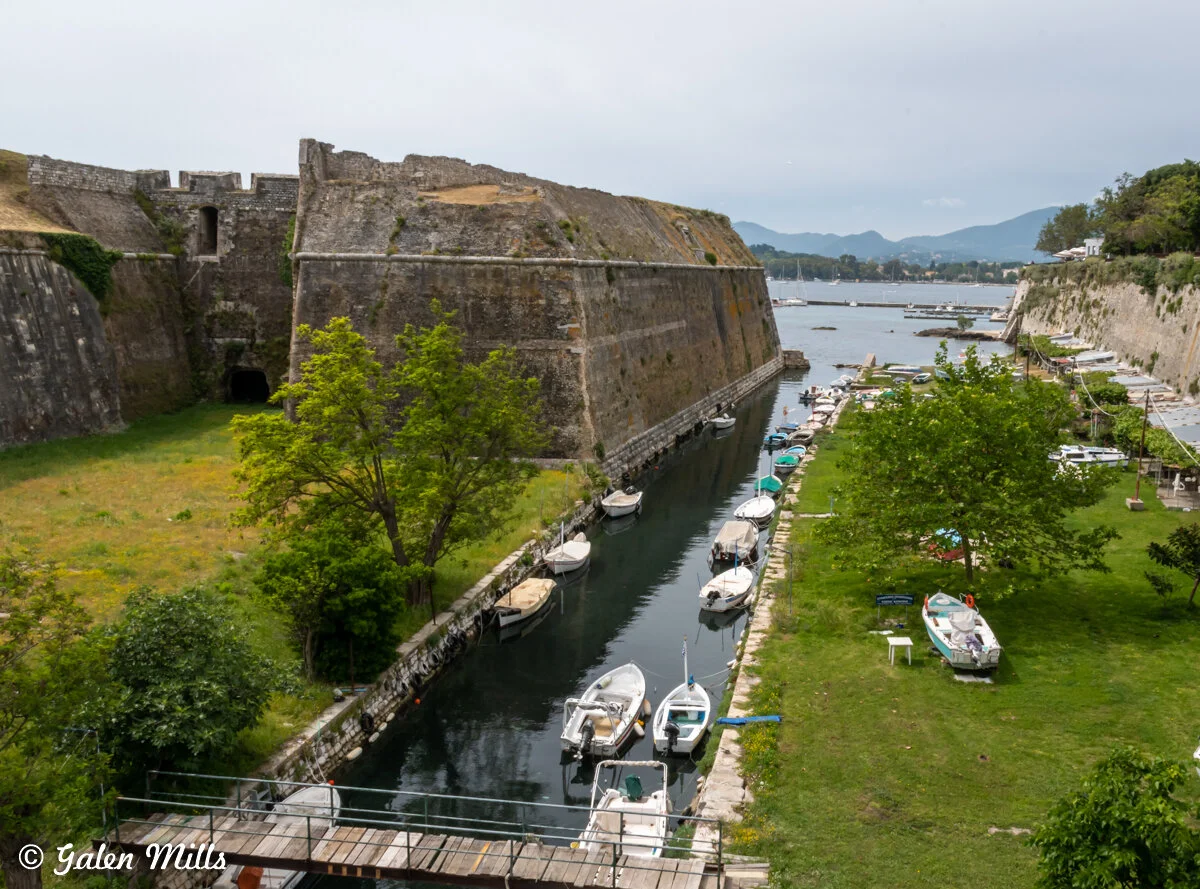Old fort with boats in canal surrounded by green landscape