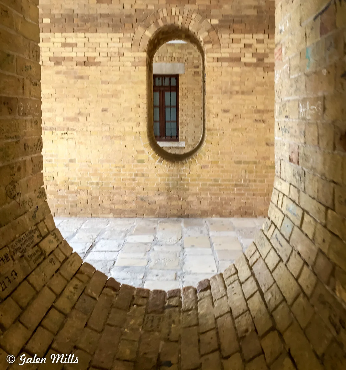 Interior of an old brick structure with arched niches and window