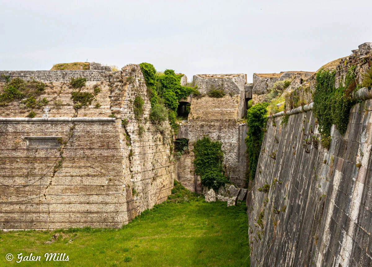 Historic stone fort walls covered in vegetation with a grassy moat