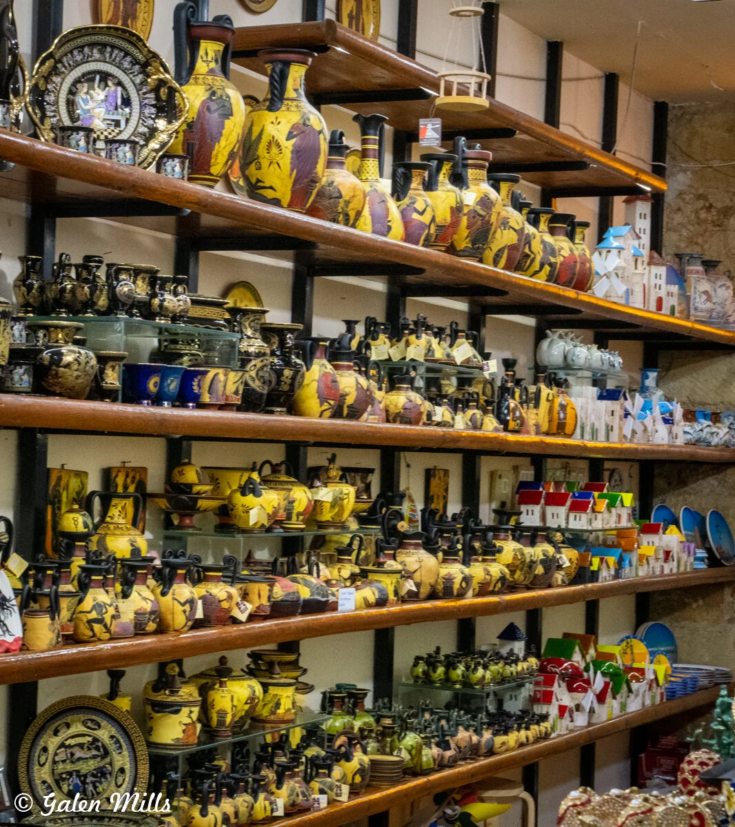 Shelves displaying decorative pottery and ceramic items, including vases with traditional designs, miniature buildings, and plates in various colors and patterns.