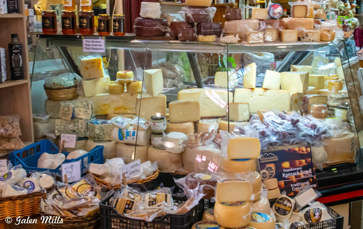 Cheese shop display with various cheese blocks, baskets, and honey jars