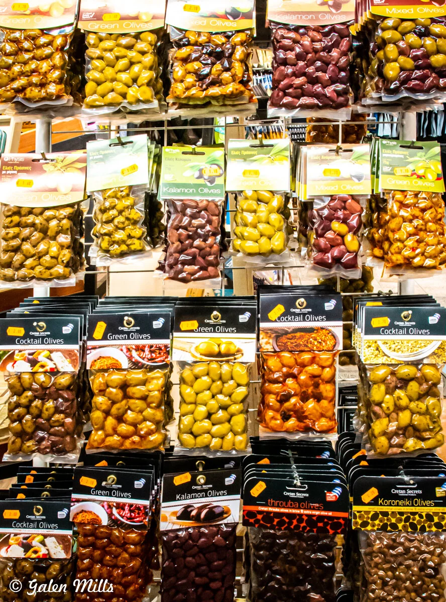 Variety of packaged olives on display, including green, Kalamon, and cocktail olives.