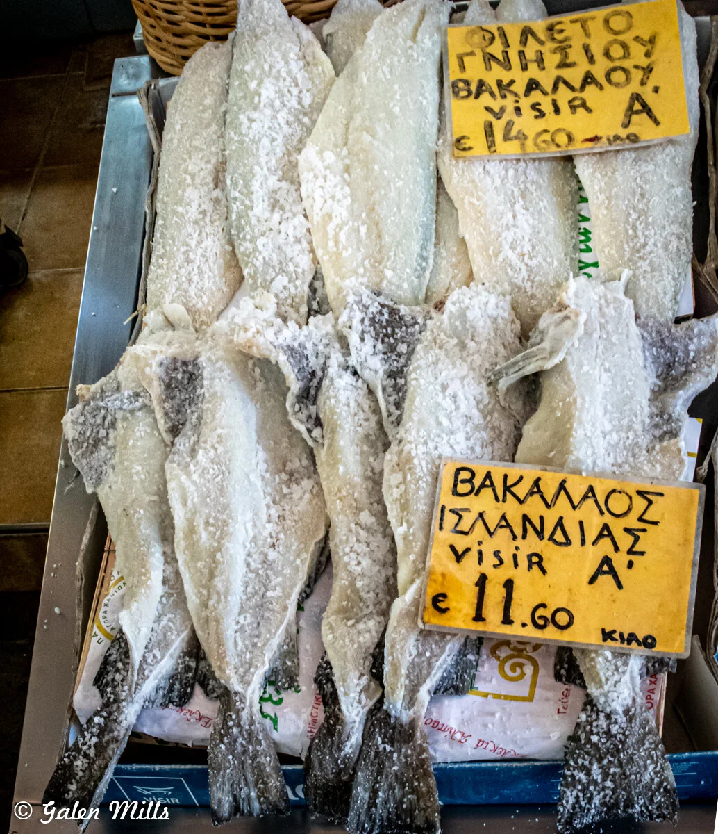 Salted codfish display with Greek signage, price per kilo.