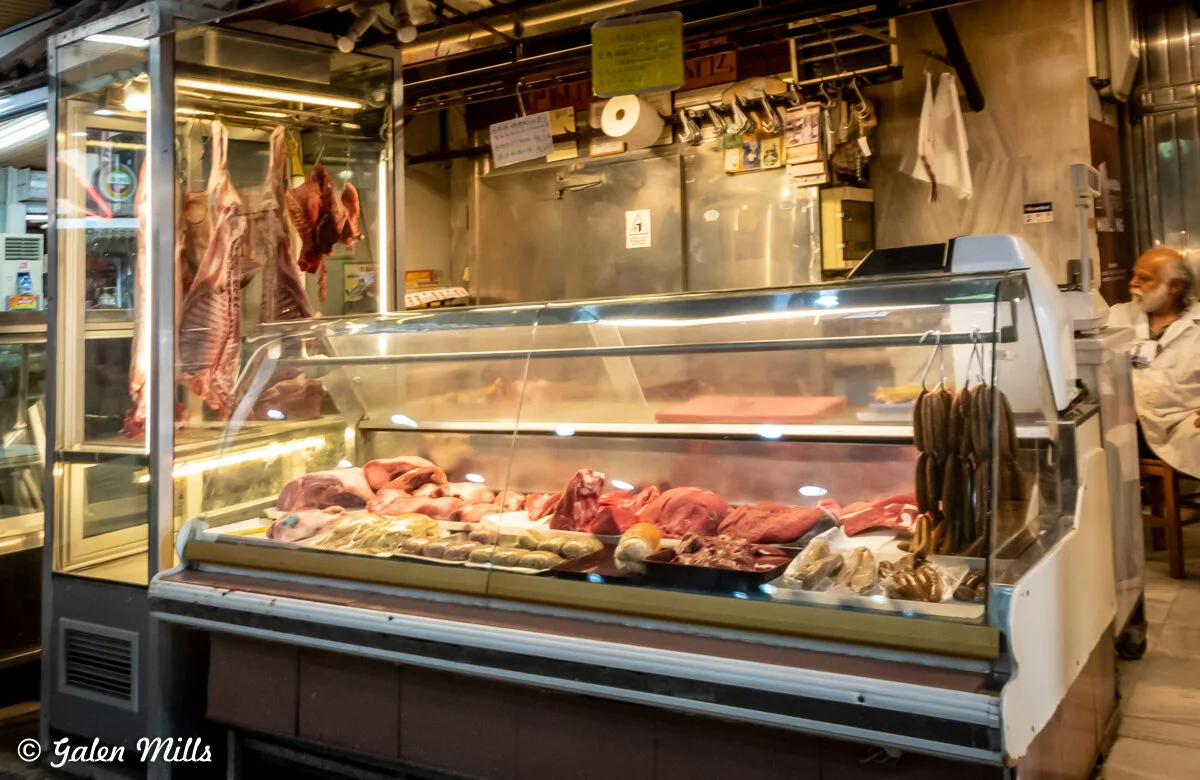 Butcher shop with meat display cases and hanging cuts of meat.