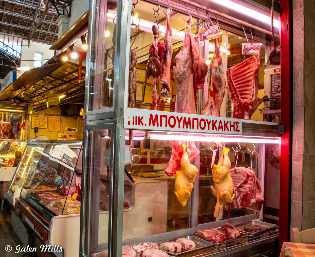 Interior of a butcher shop displaying hanging meats and poultry.