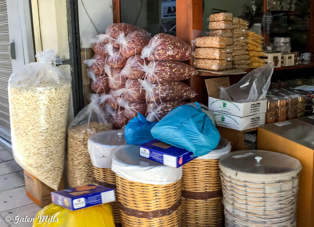 Shop display with bags of peanuts, packaged snacks, and wicker baskets.