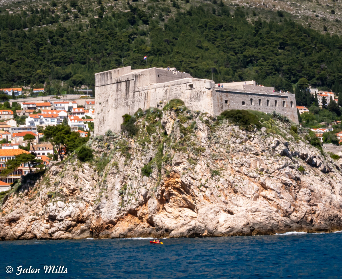 Historical fortress on rocky cliff with surrounding village and sea view