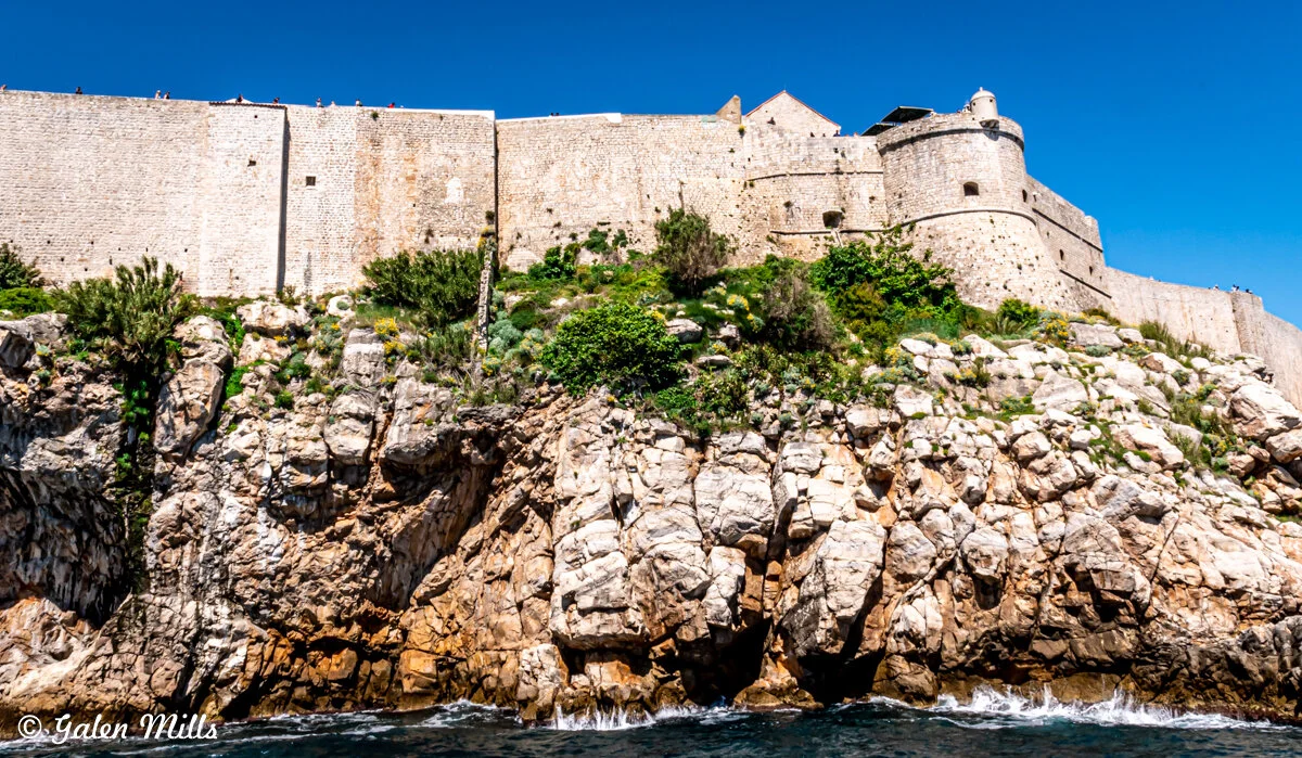 Fortress walls above rocky coastline under clear sky