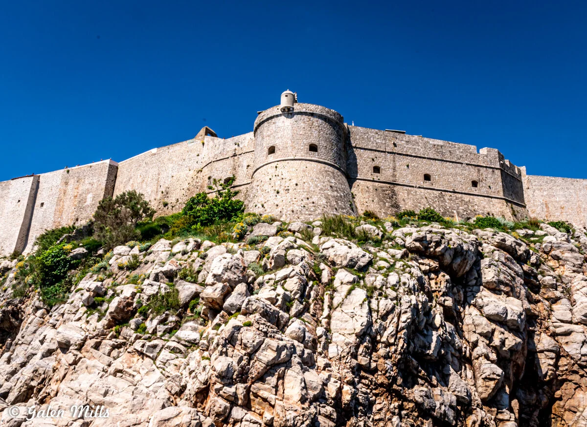 Medieval stone fortress on rocky cliff against blue sky