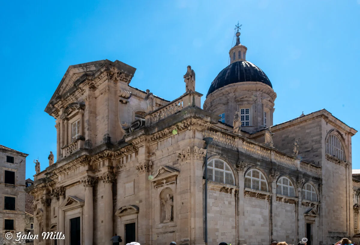Historic stone church with decorative architecture and dome under clear blue sky.