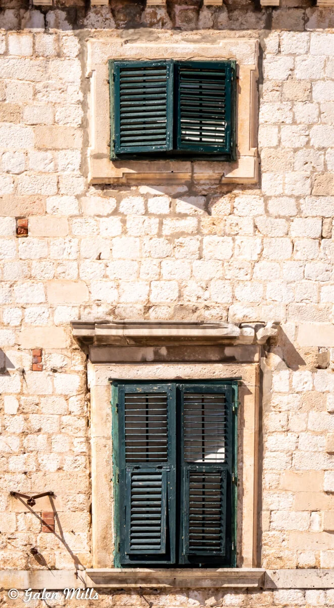 Old stone building with two wooden shuttered windows