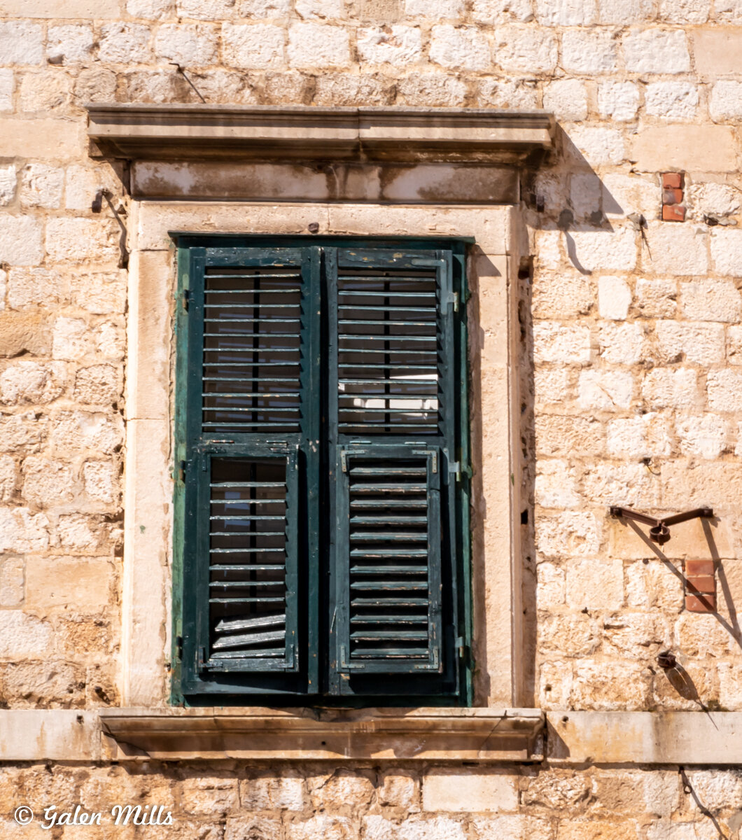 Old stone building with closed green wooden shutters