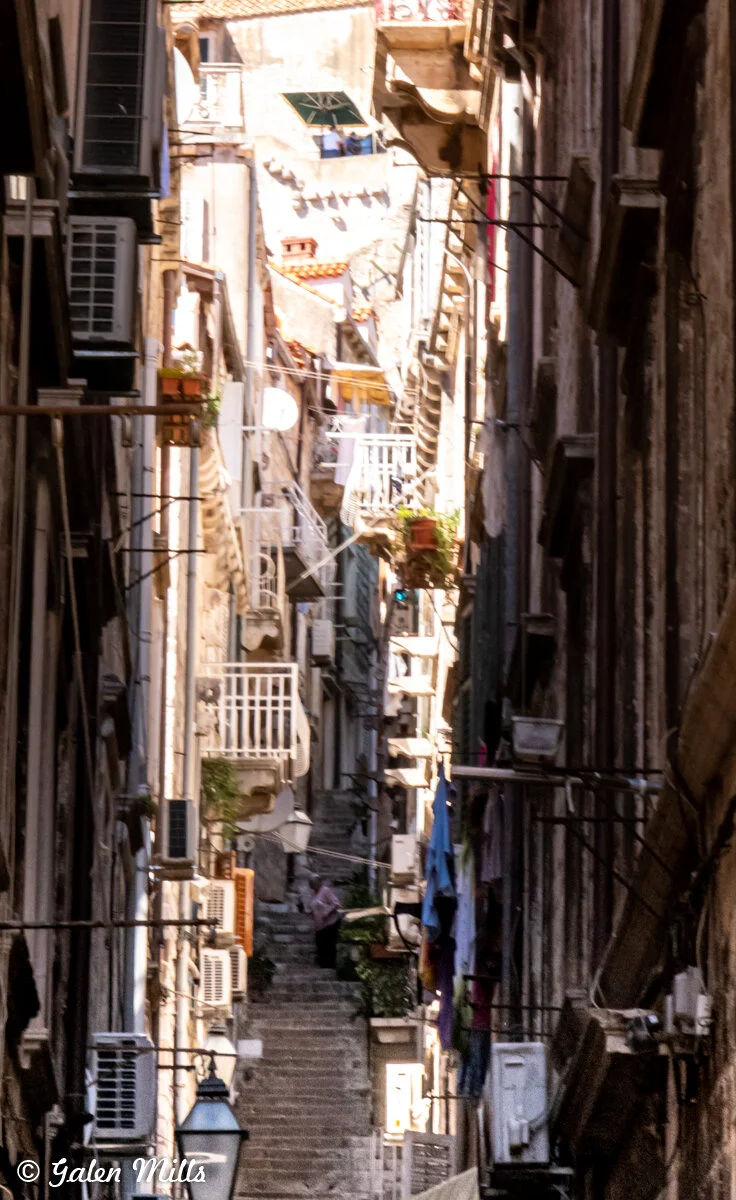Narrow stone staircase in an Italian alley with balconies and laundry hanging.