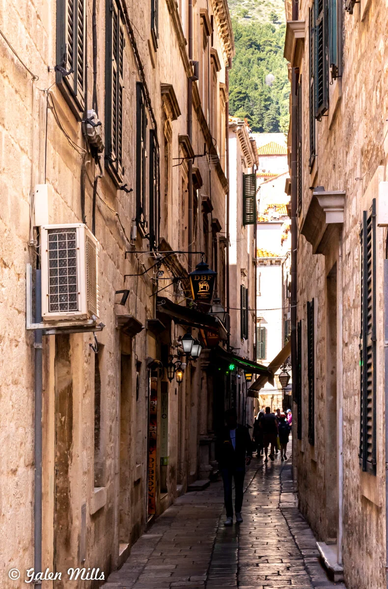 Narrow stone alley in old European city with shops and lanterns