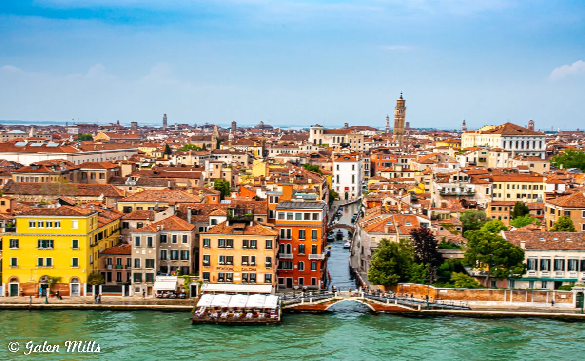 Scenic view of Venice with colorful buildings, canals, and bridges under a blue sky.