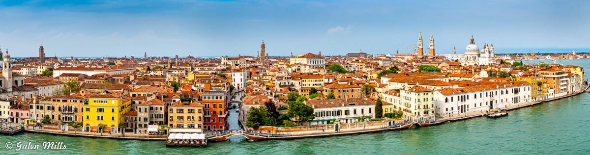 Panoramic view of Venice, Italy, showcasing colorful buildings, canals, and historic architecture with a clear sky.