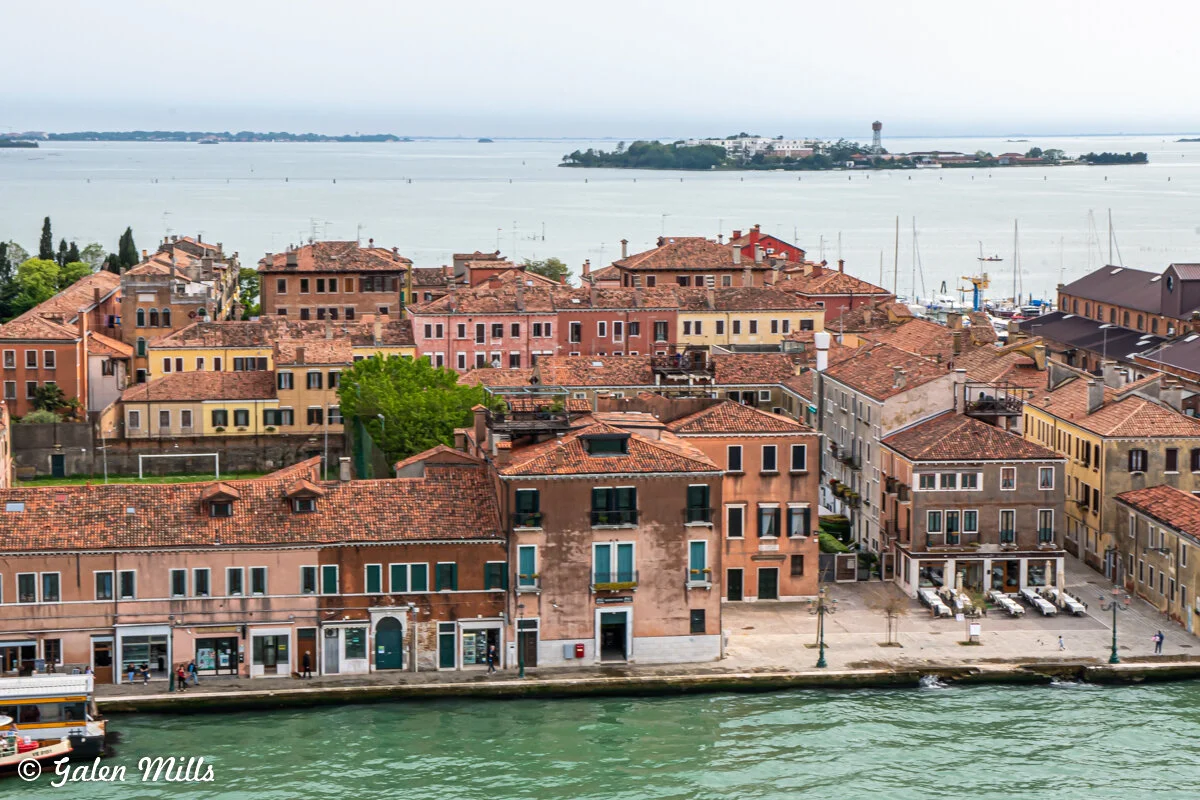 Venetian buildings near a canal with view of distant islands and water.