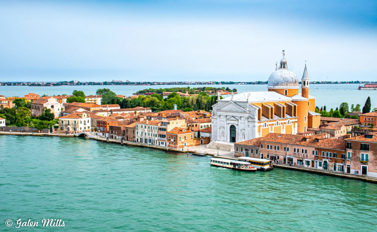 Aerial view of the island of San Giorgio Maggiore in Venice, featuring the San Giorgio Maggiore church with its dome and bell tower, surrounded by historical buildings and water.