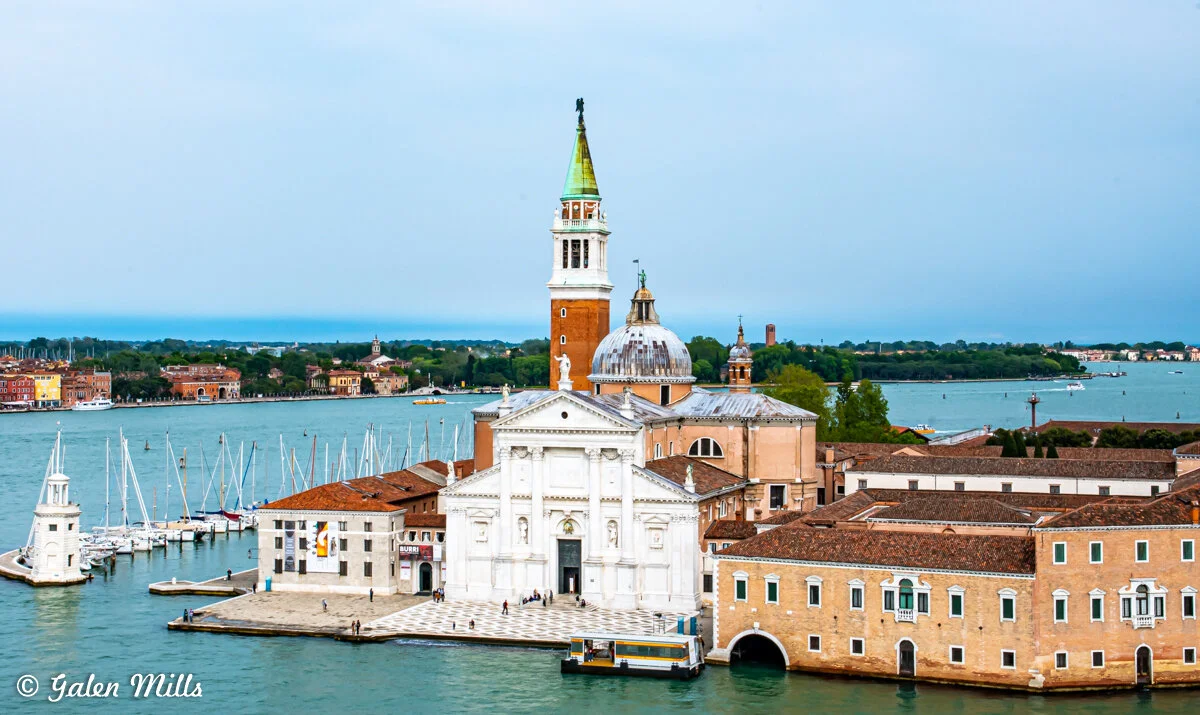 San Giorgio Maggiore island with church and bell tower in Venice, Italy, surrounded by water and boats.