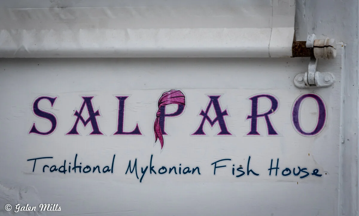 Sign for Salparo Traditional Mykonian Fish House with a logo featuring a pink headscarf.